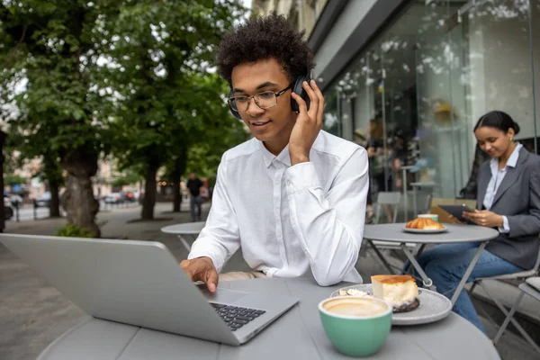 Work remotely. Young businessman with headphones working remotely and looking contented