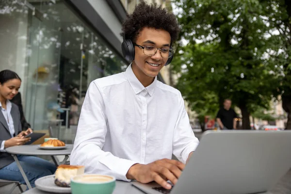 Work remotely. Young businessman with headphones working remotely and looking contented