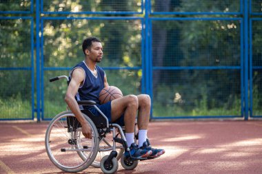 Tekerlekli sandalyedeki basketbol oyuncusunun açık alanda portresi.