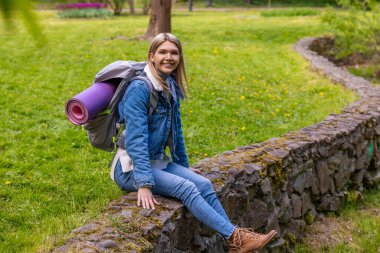 Yürüyüşten sonra dinlenin. Sarışın genç bayan uzun bir yürüyüşten sonra dinleniyor ve rahatlamış görünüyor