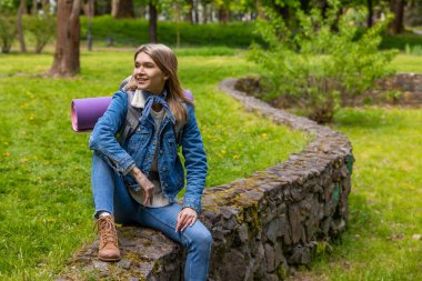 Yürüyüşten sonra dinlenin. Sarışın genç bayan uzun bir yürüyüşten sonra dinleniyor ve rahatlamış görünüyor