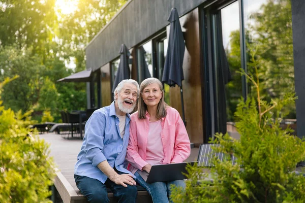 stock image Mature wife and husband using laptop with solar panel at home porch.