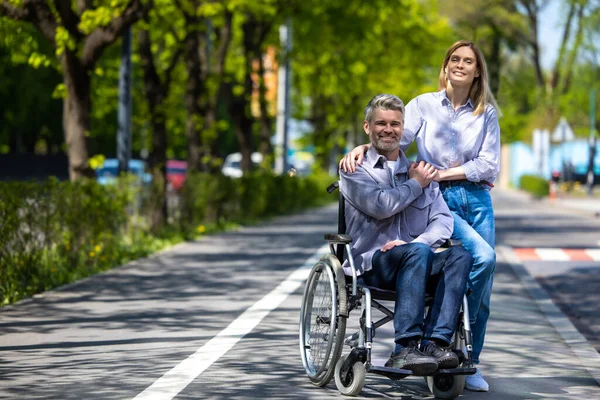 Tekerlekli Sandalyede Orta Yaşlı Bir Adam Şehirde Yürüyen Bir Kadın — Stok fotoğraf