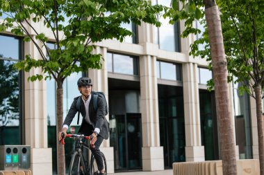 Ofise giden yol. Ofis bölgesinde bisiklet süren etekli bir adam.