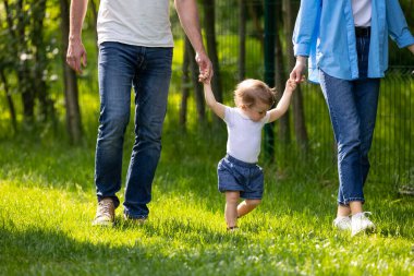 Çocukla yürü. Ebeveynler küçük sevimli oğluyla yürüyüşe çıkıyor.