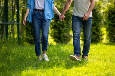 Parkta yürü. El ele tutuşan ve parkta yürüyen bir çift.