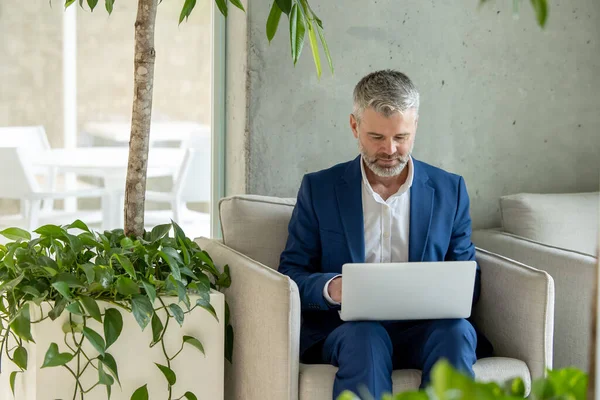 Dojrzały Mężczyzna Przedsiębiorca Pracuje Fotelu Biurze Pracując Laptopie — Zdjęcie stockowe