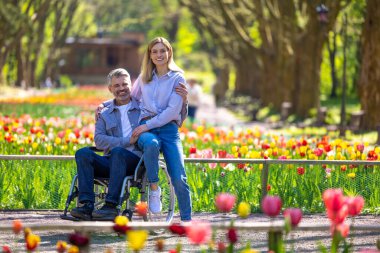 Romantik orta yaşlı eş ve tekerlekli sandalyede yürüyen engelli koca..