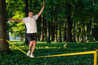 Odaklandım. Spor elbiseli genç adam ipte yürüyor ve odaklanmış görünüyor.