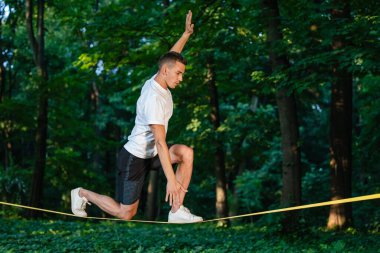 Odaklandım. Spor elbiseli genç adam ipte yürüyor ve odaklanmış görünüyor.