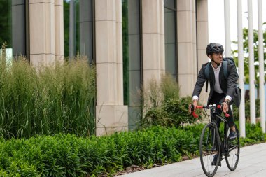 Morning ride. Businessman riding a bike and looking contented clipart