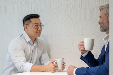 İki işadamı kahve molası verip ofiste iş stratejilerini tartışıyor..