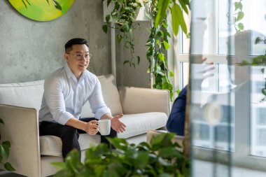 İki işadamı mola verip kahve içer ve dinlenme odasında iş stratejisini tartışır..