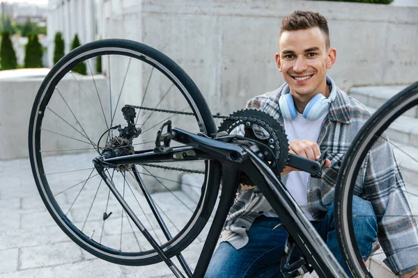 自行车修理 笑着用自行车车轮修理问题的年轻人 — 图库照片
