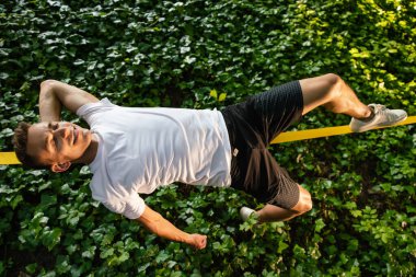 Halatla kayma. Gülümseyen genç yakışıklı adam ipte yatıyor ve dengesini koruyor.