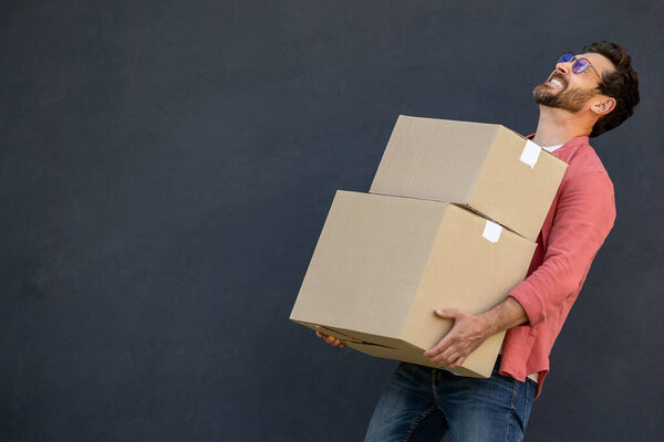 Man with boxes. Contented young ma with heavy carton boxes in hands