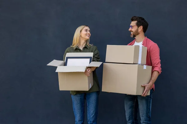 Move to new house. Young couple moving to a new house and carrying boxes with clothes