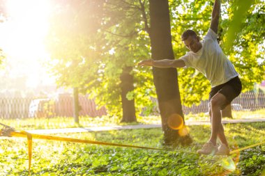 Halatla kayma. Genç adam ormanda ipte dengede duruyor.