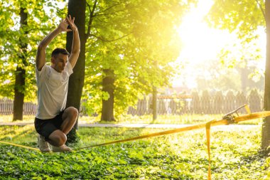 Halatla kayma. Genç adam ormanda ipte dengede duruyor.