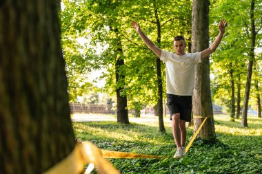 Halatla kayma. Genç adam ormanda ipte dengede duruyor.