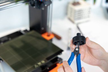3D yazıcıyı kontrol eden adama yakın çekim, laboratuvarda 3D yazıcıda bir şeyler yapma süreci.