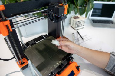 3D yazıcıyı kontrol eden adama yakın çekim, laboratuvarda 3D yazıcıda bir şeyler yapma süreci.