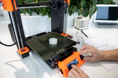 3D yazıcıyı kontrol eden adama yakın çekim, laboratuvarda 3D yazıcıda bir şeyler yapma süreci.