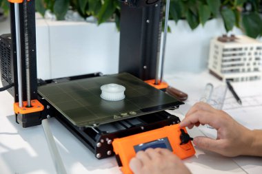 3D yazıcıyı kontrol eden adama yakın çekim, laboratuvarda 3D yazıcıda bir şeyler yapma süreci.