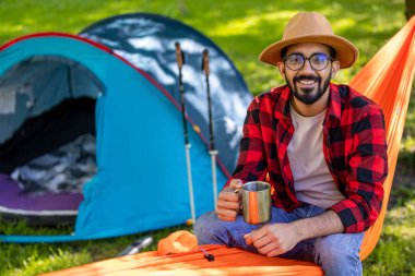 Rahatlamış hissediyorum. Hasır şapkalı sakallı genç adam hamakta rahatlamış hissediyor.