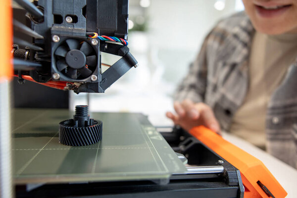 Closeup of man checking 3d printer, process of making things on 3d printer in laboratory.