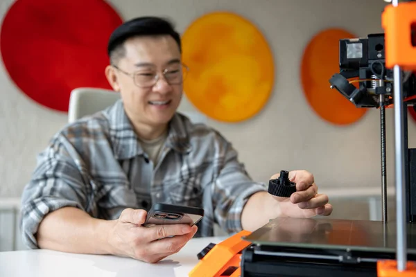 亚洲深色头发男子设计师手握打印在工程车间3D打印机上的契约 — 图库照片