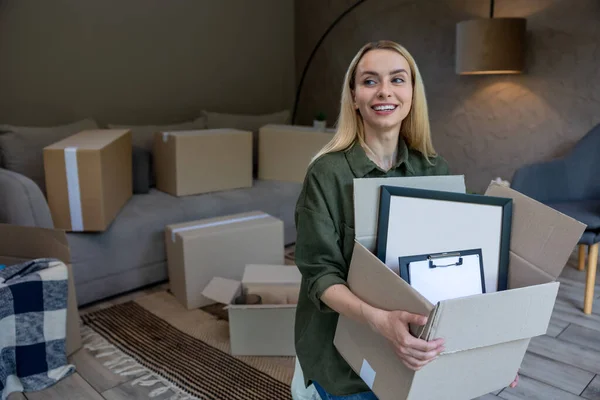 Packing. Smiling blonde woman with a box in hands