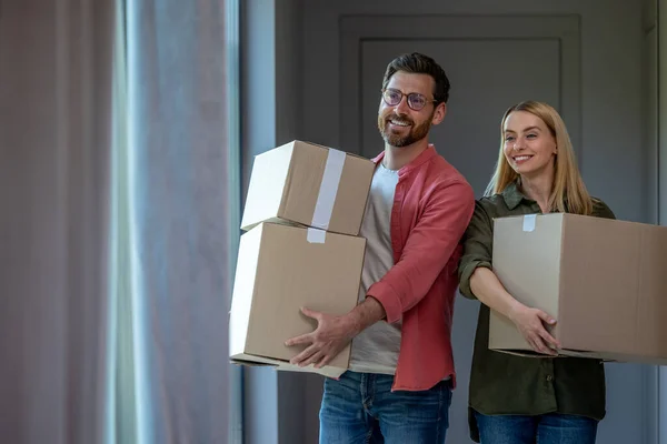 两对年轻夫妇在搬迁时携带着带有衣服的纸板 — 图库照片