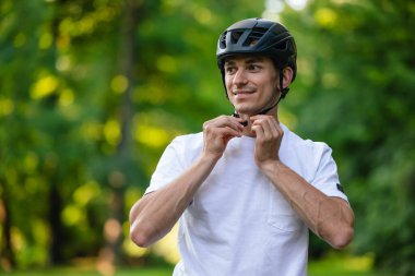 Koruyucu hemlet. Genç yakışıklı bisikletçi koruyucu eteğini giyiyor.