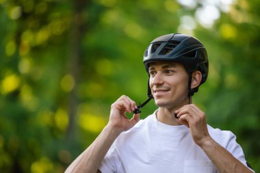Koruyucu hemlet. Genç yakışıklı bisikletçi koruyucu eteğini giyiyor.