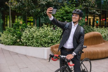 Scooter 'da selfie. Gülümseyen iş adamı mobiletle selfie çekiyor.