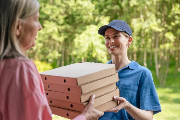 Food Delivery. Female courier delivering pizza to client home.