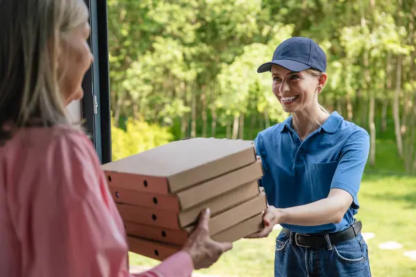 Food Delivery. Female courier delivering pizza to client home.