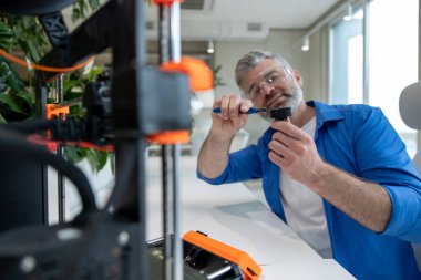 Ofiste 3D yazıcı kullanan olgun erkek tasarımcı yazdırma tasarımı.