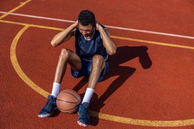 Spor yapan atletik siyah adam, mekik ve mekik çekiyor. Basketbol sahasında karın kaslarını çalıştırıyor..