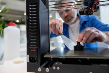 Ofiste 3D yazıcı kullanan olgun erkek tasarımcı yazdırma tasarımı.