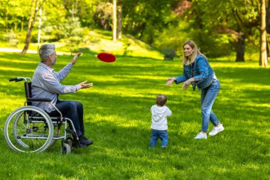 Frizbi oyunu. Parkta frizbi oynayan sevimli bir aile.