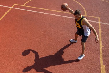 Atletik erkek sporcu basketbol oynuyor. Oyun alanına top atıyor, alanı kopyalıyor..