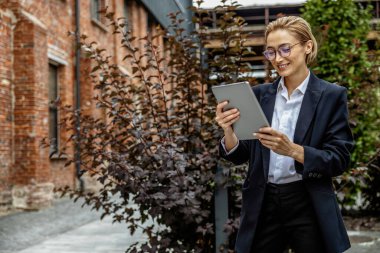 Zarif kadın. Bahçesinde tableti olan zarif genç bir iş kadını.