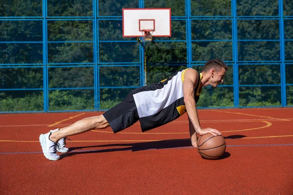 在篮球场上做俯卧撑的成年人的侧视图 — 图库照片