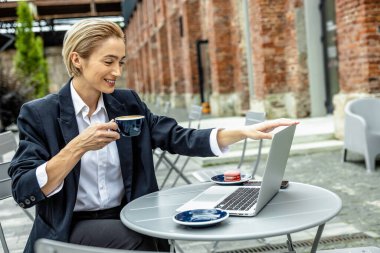 Uzaktan çalışıyor. Genç, sarışın, laptopta çalışan ve ilgili görünen bir kadın.