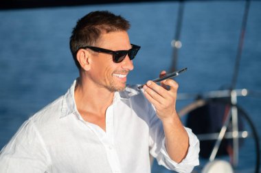 Sesli mesaj. Güneş gözlüklü adam bir sesli mesaj kaydediyor.