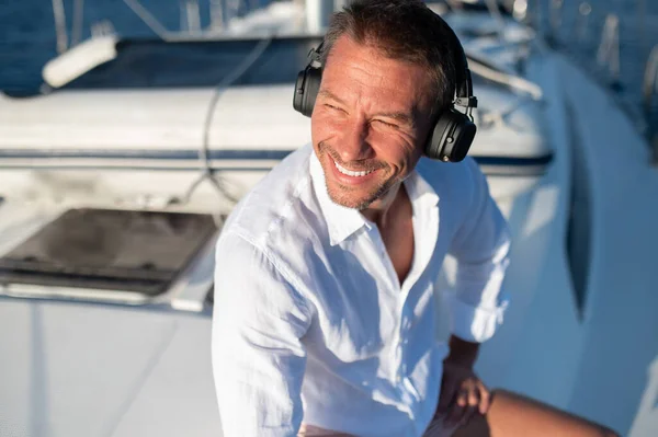 On a yacht. Happy man in headphones listening to music while sailing on a yacht