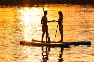 Deniz kadını ve güvertedeki adam denizde ya da nehirde dinleniyorlar..