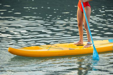 Okyanusta suyun üstünde yüzen kürekle tanınmayan bir kız..